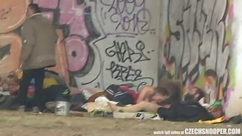 A Threesome Of Homeless Individuals Engage In Sexual Activity On The Streets In A European Suburb